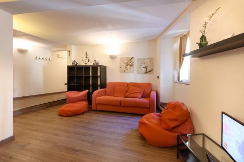 a living room with an orange couch and a tv at Hotel Garni Le Corti in Grosotto