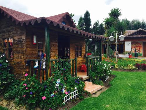 a small wooden house with flowers in a yard at Casa d'Campo Tababela Hotel Boutique in Tababela