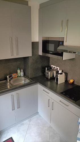 une cuisine avec des armoires blanches et un évier dans l'établissement Studio a 3min a pied des plages et proche de Cannes, à Mandelieu-la-Napoule