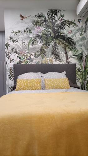 - une chambre avec un lit jaune orné d'une fresque murale en palmier dans l'établissement Studio a 3min a pied des plages et proche de Cannes, à Mandelieu-la-Napoule