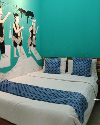 a bedroom with a bed with a painting on the wall at Villa Tamu Ibu in Beran-kidul