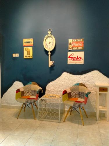a room with two chairs and a bed and a clock at Villa Tamu Ibu in Beran-kidul