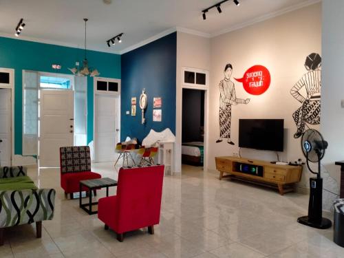 a living room with red chairs and a television at Villa Tamu Ibu in Beran-kidul