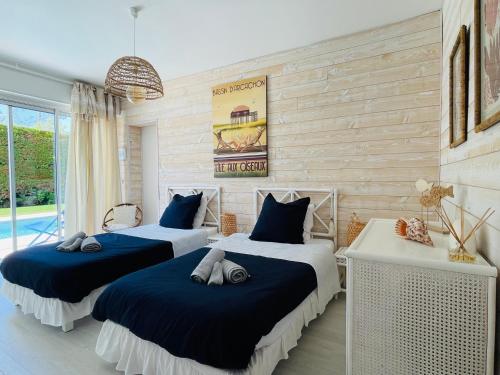 - une chambre avec 2 lits avec des draps bleus dans l'établissement Villa de Mer, première ligne, plage et piscine, à Lège-Cap-Ferret