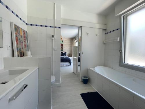 une salle de bain blanche avec une baignoire et un lavabo dans l'établissement Villa de Mer, première ligne, plage et piscine, à Lège-Cap-Ferret