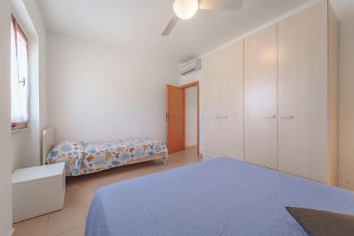 a white bedroom with a bed and a cabinet at Appartamenti Gli Orizzonti - Goelba in Marina di Campo