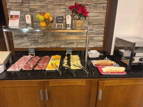 a buffet with different types of food on a counter at Hotel Euròpa Dolomites in Selva di Val Gardena
