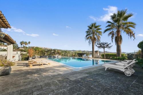 une piscine bordée de palmiers et une villa dans l'établissement Villa St Paul La Piscine, à La Colle-sur-Loup