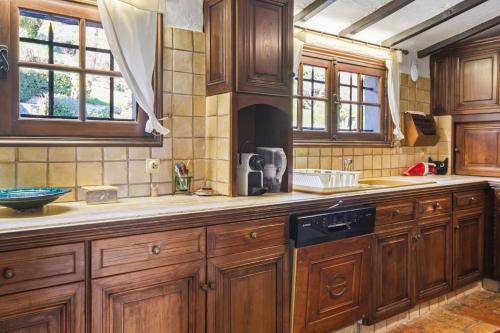 - une cuisine avec des placards en bois et un lave-vaisselle noir dans l'établissement Villa St Paul La Piscine, à La Colle-sur-Loup