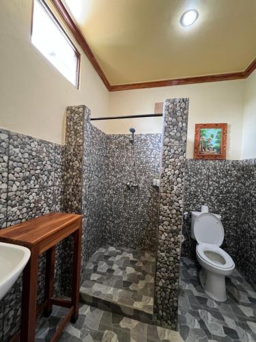 a bathroom with a shower with a toilet and a sink at Guesthouse Gusti Putu Oka in Ubud