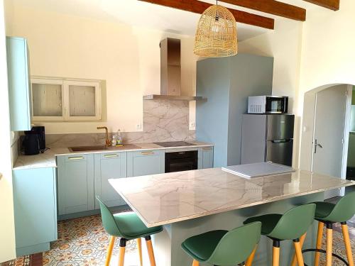 une cuisine avec comptoir et tabourets de bar verts dans l'établissement Maison avec WIFI, jardin, terrasse à l'ILE GRANDE - PLEUMEUR-BODOU - Réf 270, à Pleumeur-Bodou