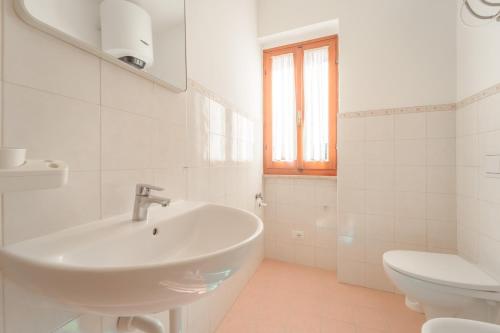 a white bathroom with a sink and a toilet at Appartamenti Gli Orizzonti - Goelba in Marina di Campo