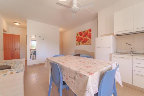 a kitchen and dining room with a table and blue chairs at Appartamenti Gli Orizzonti - Goelba in Marina di Campo