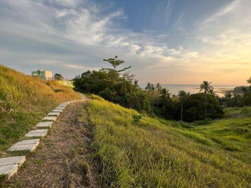a path on a hill with the ocean in the background at A & L Resort - Sea & Mountain View in Looc