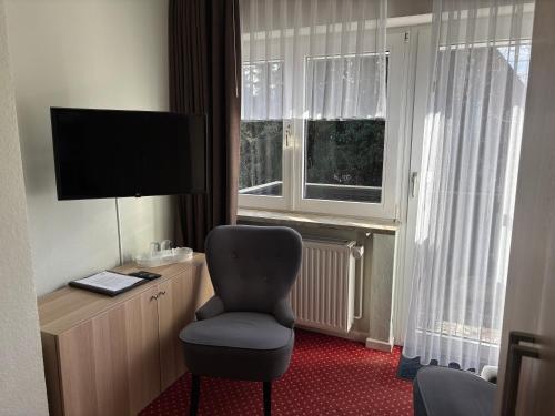 a hotel room with a chair and a television at Hotel Haus am Hochwald in Hahnenklee-Bockswiese