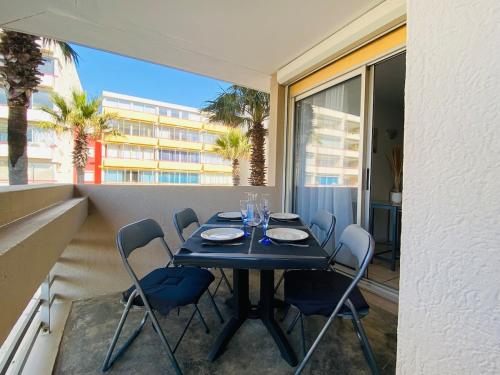 une table et des chaises noires sur un balcon avec un bâtiment dans l'établissement Canet appartement à 100 m de la plage avec parking, à Canet