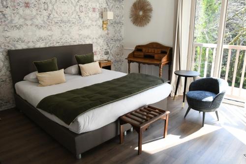a bedroom with a bed and a chair and a window at Le Moulin Des Ruats in Avallon
