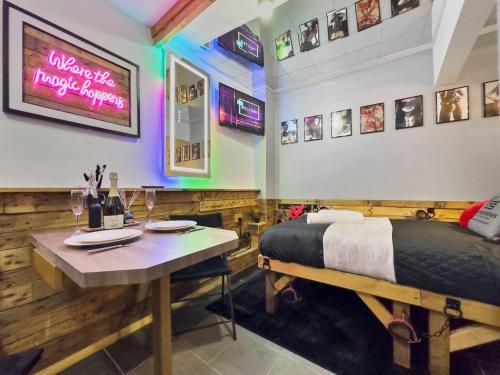 una camera con un letto e un tavolo con bicchieri da vino di Kinky Kabin W Hot Tub, Sauna And Rooftop Garden a Llwyn-y-pia