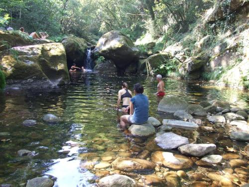 a group of people sitting on rocks in a stream at Tienda de Campaña en Ecoaldea Vegana Espiral en Plena naturaleza con comida y cena incluida in Passos