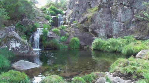 a waterfall and a pool of water in a river at Tienda de Campaña en Ecoaldea Vegana Espiral en Plena naturaleza con comida y cena incluida in Passos