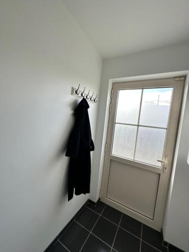 a black coat hanging on a wall next to a door at De Karlapper in Lokeren