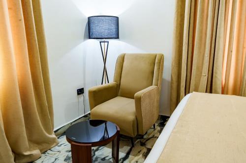 a room with a chair and a lamp next to a bed at Roston Hotels in Port Harcourt