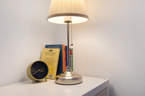 a lamp on a table with books and a clock at Casa vacanze Le More in Cares