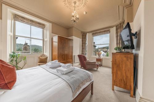 a bedroom with a bed and a tv and two windows at 1869 - Room Only Boutique Townhouse in Ambleside