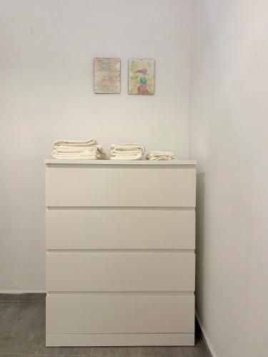 a white dresser against a white wall with two pictures at Il Vicolo, 200m dal centro storico, 25 min da Roma in Monterotondo