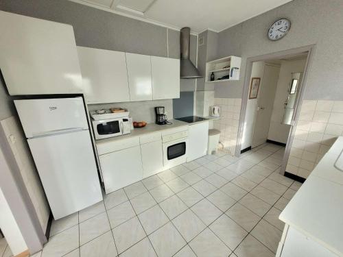 La cuisine est équipée de placards blancs et d'un réfrigérateur. dans l'établissement Charmante maison plain-pied à Berck, jardin sud, proche plage, animaux admis - FR-1-674-20, à Berck-sur-Mer
