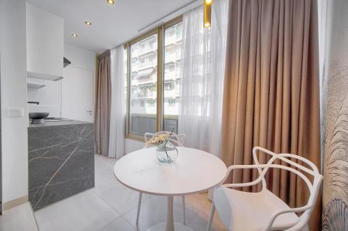 une table blanche et des chaises dans une pièce avec une fenêtre dans l'établissement Palace - Ultra center - 2 min sea - VCA, à Cannes