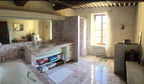 une salle de bain avec une baignoire, un lavabo et un miroir dans l'établissement L'évasion Provencale, à Saze