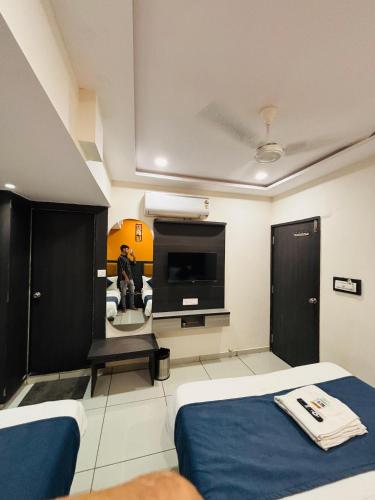 a hotel room with two beds and a flat screen tv at Hotel Sunview in Ahmedabad