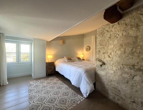ein Schlafzimmer mit einem Bett und einer Steinwand in der Unterkunft ORIANE maison de charme proche Plage in Sainte-Marie-de-Ré