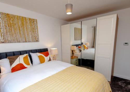 a bedroom with a large white bed with orange pillows at Manchester Cityside Deluxe Stay - 3 Bedroom House Great for Family with Free Parking & Garden in Manchester