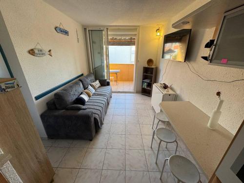 un salon avec un canapé et une table dans l'établissement Charmant T2 avec piscine et parking privatif au Cap d'Agde, idéal pour 4 personnes - FR-1-749-72, au Cap d'Agde