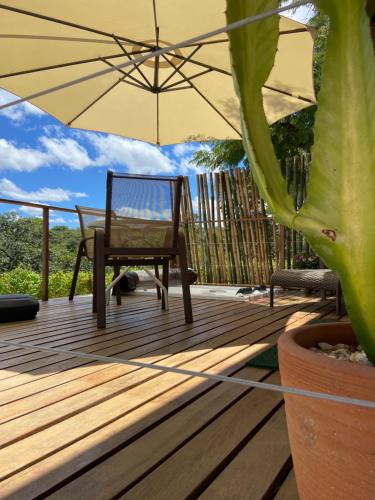 a wooden deck with a chair and an umbrella at Chalé Makar in Serra do Cipo