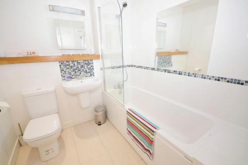 Un baño blanco con inodoro y ducha. en The Sanctuary, en Sandown