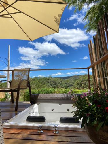 a hot tub on a deck with an umbrella at Chalé Makar in Serra do Cipo
