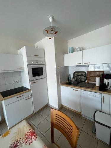 une cuisine avec des armoires blanches et un four à plaques de cuisson dans l'établissement Les Astéries 24 - Duplex, à Quend-Plage