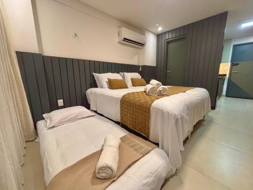 a hotel room with three beds with towels on them at UMI Flats - Intermares in Cabedelo