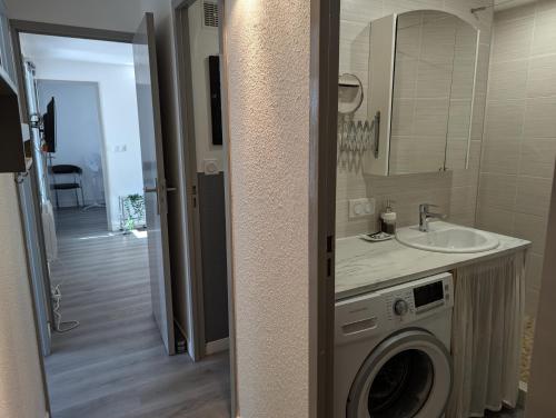 une salle de bain avec une machine à laver et un lavabo dans l'établissement Sol-y-Days Sloop appartement 2 chambres avec parking, au Grau-du-Roi
