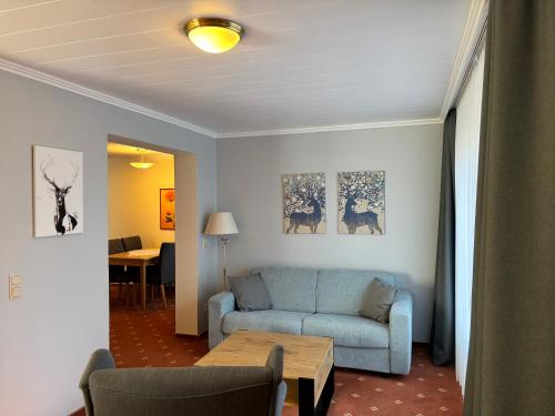 a living room with a blue couch and a table at Hotel Haus am Hochwald in Hahnenklee-Bockswiese