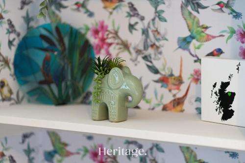 a green elephant figurine on a shelf with a plant at The Copper Loft Apartment, Keith in Keith