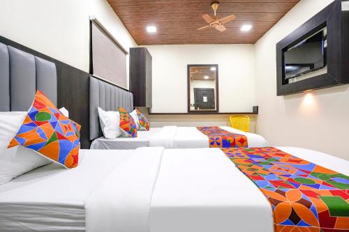 a bedroom with two beds and a tv at FabExpress Gulshan Grand - Nr Gateway of India in Mumbai
