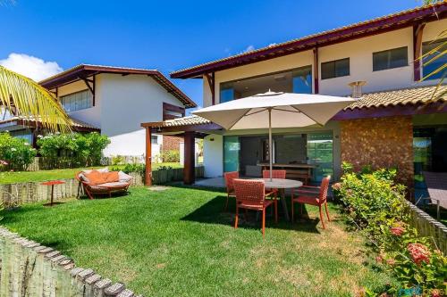 a patio with a table and chairs and an umbrella at Ykutiba Imbassaí - Bangalô - J02 in Imbassai