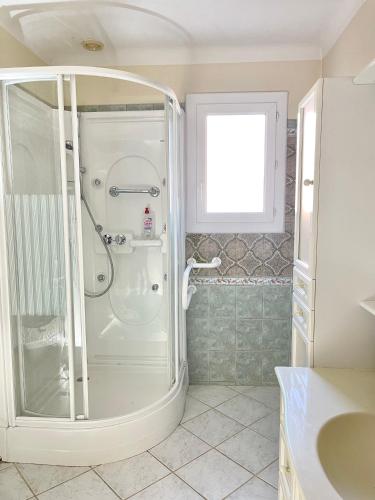 La salle de bains est pourvue d'une douche blanche et d'une fenêtre. dans l'établissement Grand Appartement Provençal, à Manosque