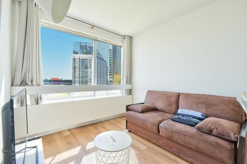 un salon avec un canapé et une grande fenêtre dans l'établissement Beautiful Studio at La Défense near Paris, à Puteaux