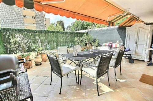 - une table et des chaises sur une terrasse avec un parasol dans l'établissement magnifique 2 pièces parc de la croisette, à Cannes