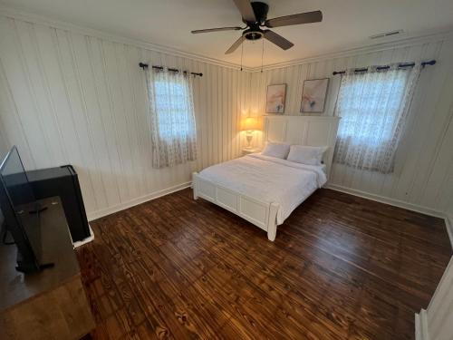 Un dormitorio con una cama blanca y un ventilador de techo. en Private Room in Milledgeville, en Milledgeville